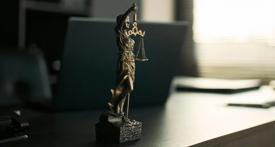 Nahaufnahme der Justizia auf einem Schreibtisch in einer Anwaltskanzlei.